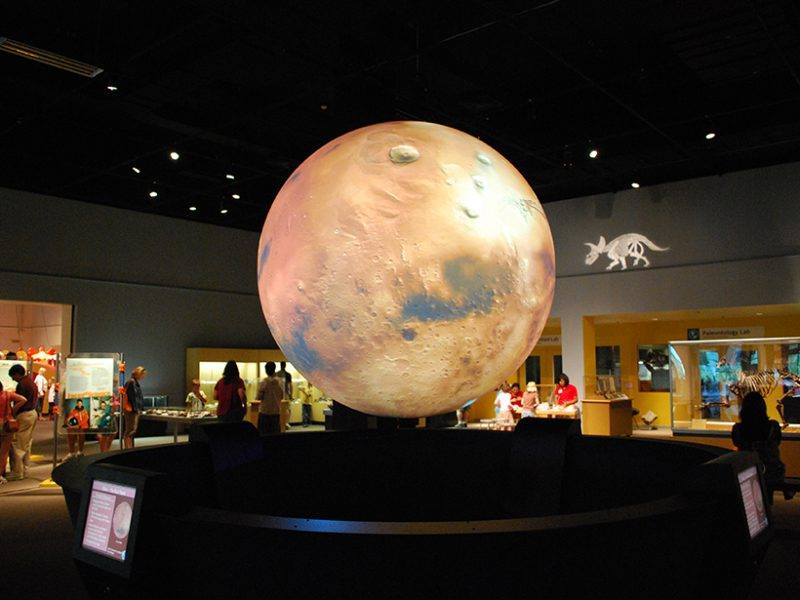 darkened room in a museum with a large lighted sphere in the center