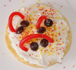 A cookie with frosting, licorice, sprinkles and m&m's.