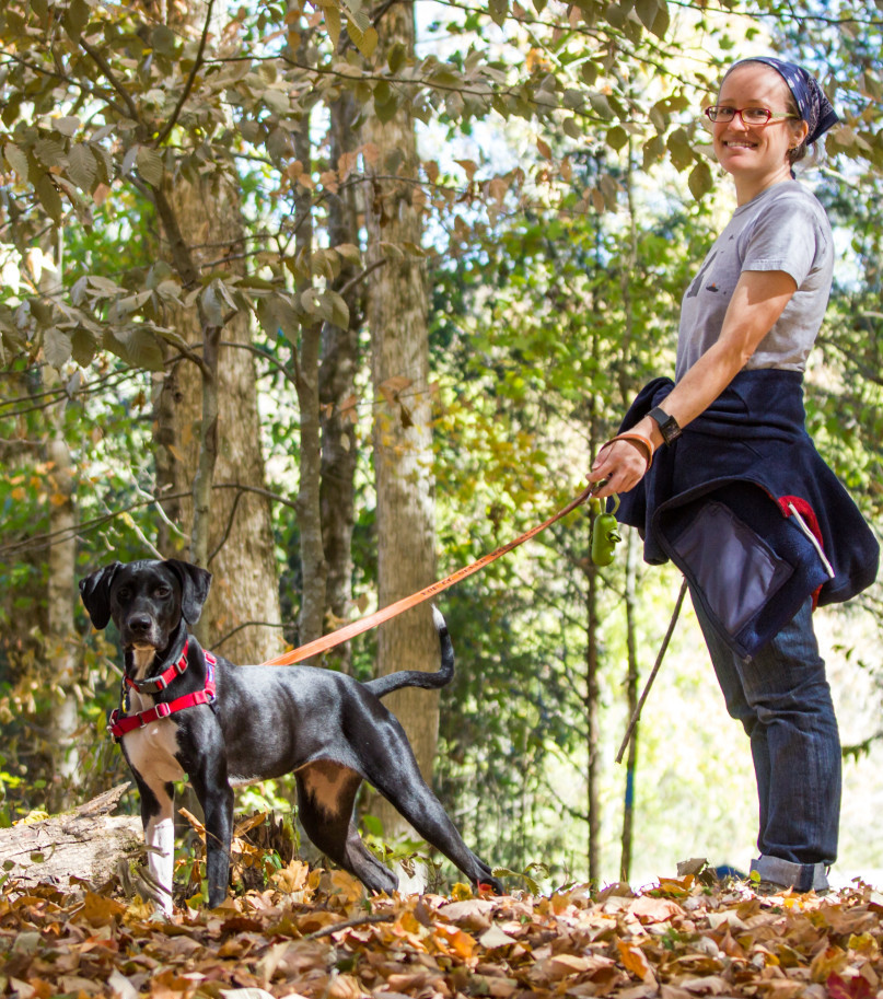 smiling woman with dog in woods